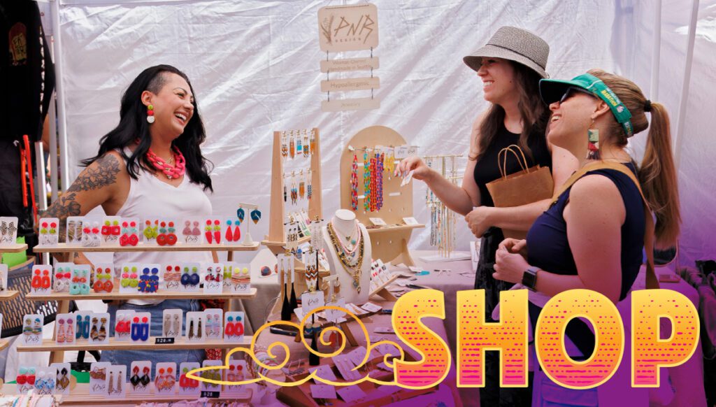 Three women interact at a jewelry booth at an outdoor market, with colorful earrings and necklaces displayed; the word "SHOP" is bold in the foreground.