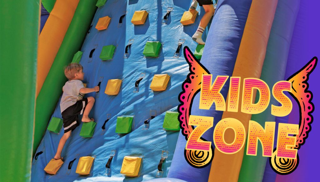 A child climbs a colorful inflatable wall with "Kids Zone" text and decorative accents on the right side.