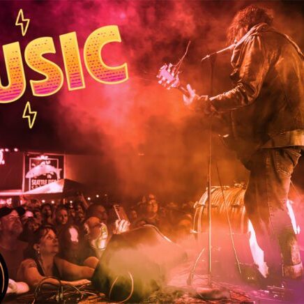 Musician plays guitar on stage with colorful lights and fog, while a crowd watches. The word "MUSIC" is highlighted in bold letters with a graphic guitar illustration.
